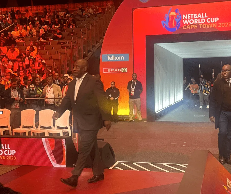 A guest in a suit walks onto the court at the Netball World Cup in Cape Town, with the crowd behind